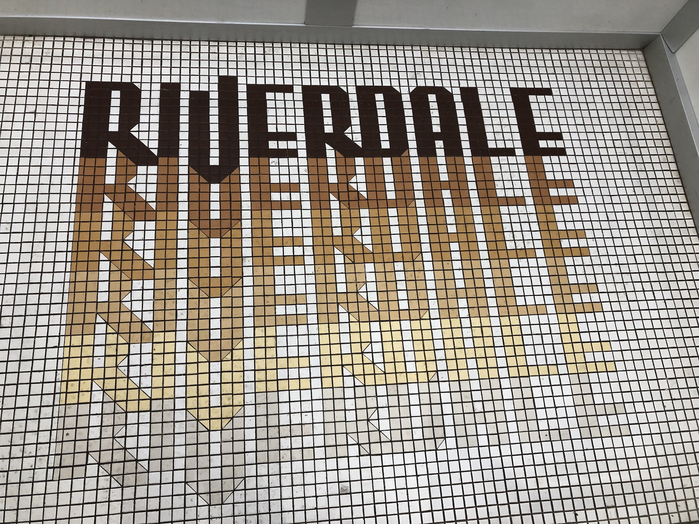 The floor of the elevator, which says "Riverdale" in vintage brown, orange, and yellow lettering. 